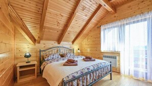 Un dormitorio de cabaña de madera con cama, mesita de noche y ventana.