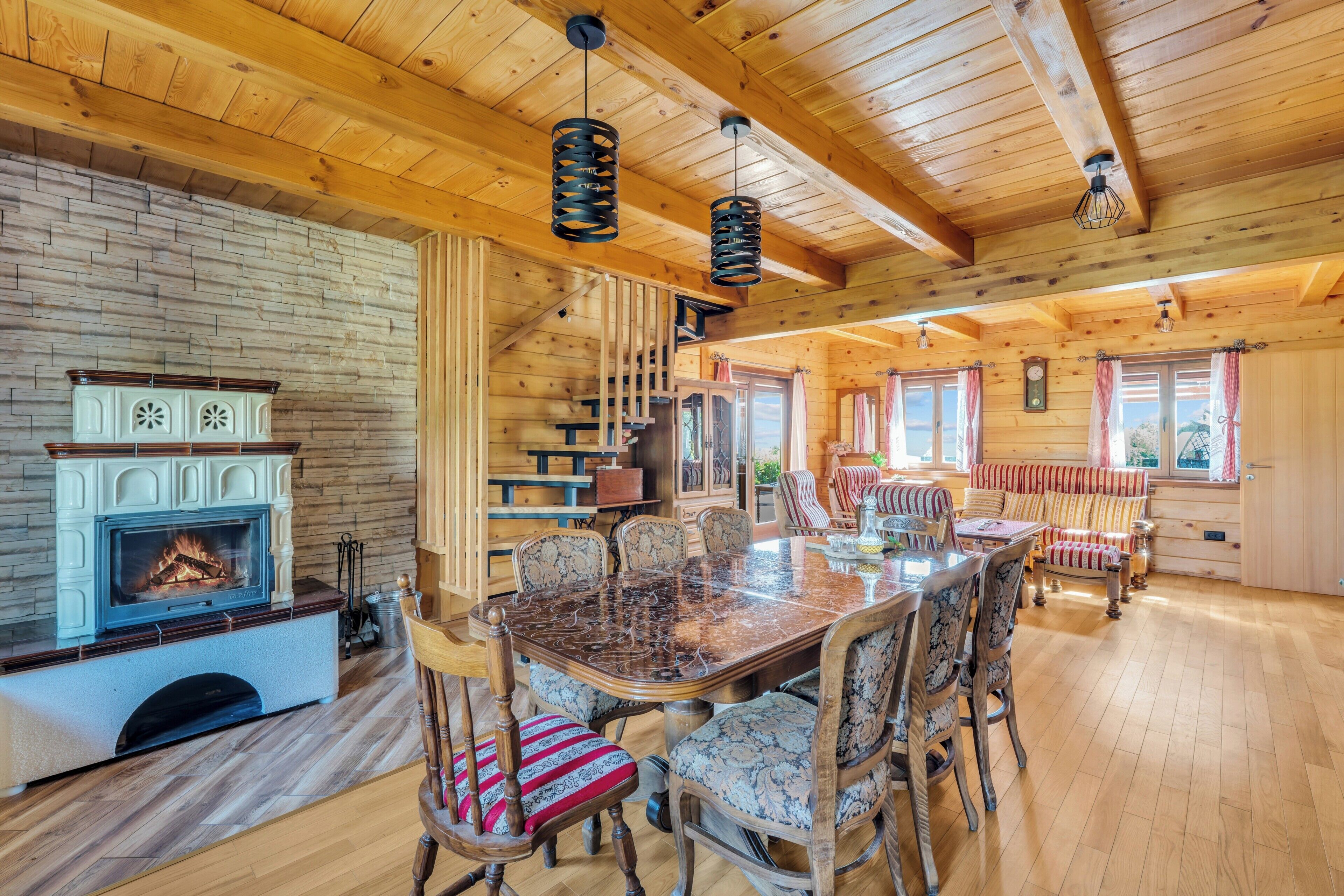 A cozy wooden interior with a fireplace, dining table, and chairs.