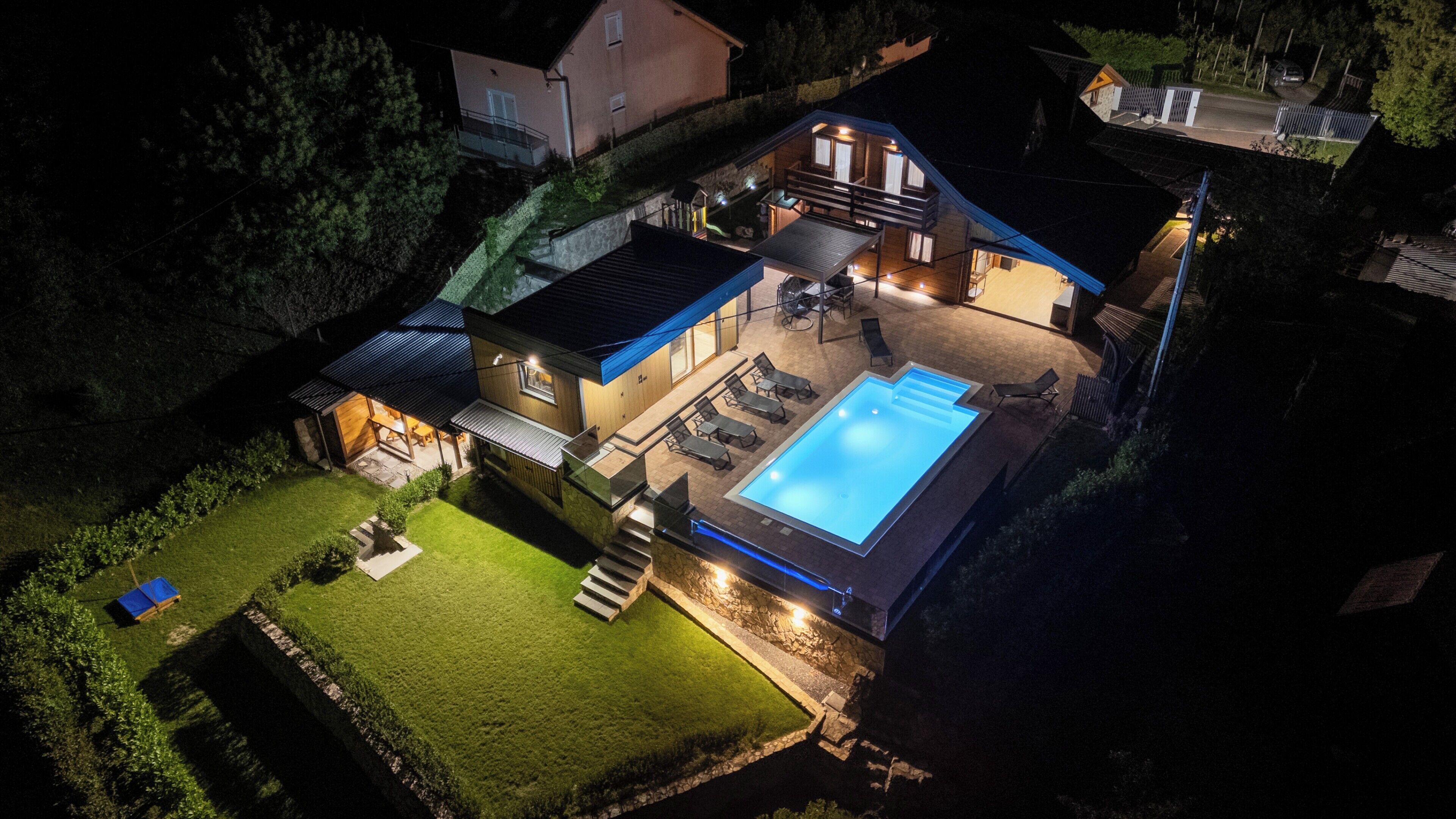 Et toetagers hus med swimmingpool, udendørs siddepladser og en godt oplyst patio.