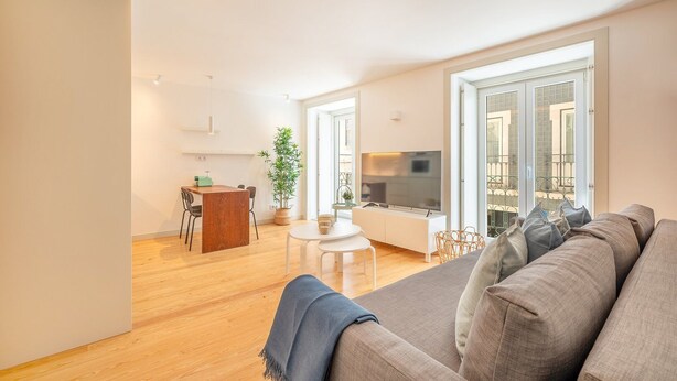 A modern living room with a sofa, a dining area, and a TV.