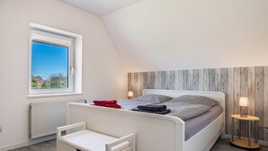 Una camera da letto con un letto, una finestra, un termosifone, un comodino e una piccola sedia.