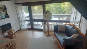 Een woonkamer met een bank, een televisie, een tafel en een vloerkleed.