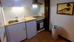 Een kleine keuken met witte kastjes, een spoelbak, een vaatwasser en een kookplaat.