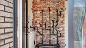 A brick wall with exposed pipes and a clock, a sign reading 'Garderobe,' and a door with a radiator. - Apartment 'Fewo Kaso' with Private Garden, Wi-Fi and Air Conditioning (Ihlow)