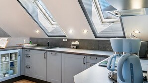 A modern kitchen with skylights, a coffee maker, and a sink. - Apartment 'Fewo Kaso' with Private Garden, Wi-Fi and Air Conditioning (Ihlow)