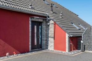 Ein Gebäude mit roter Fassade, einem Ziegeldach und einer Tür mit Fenster.