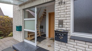 Een modern gebouw met een glazen deuropening, een trap en een brievenbus met de tekst 'BRIEFKASTEN'.