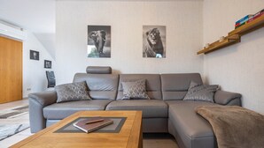 Een moderne woonkamer met een grijze bank, een houten salontafel en twee ingelijste foto's van dieren aan de muur.