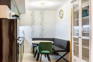 A kitchen with a refrigerator, a dining table with chairs, a built-in bench, and a cabinet with glass doors.