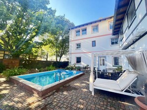 A swimming pool, lounge chairs, and a building with multiple windows.