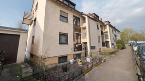 A multi-story residential building with balconies, a gated driveway, and parked cars. - New Central Apartment with Wi-Fi in Stuttgart (Stuttgart)