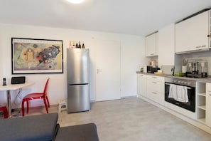 Eine kleine Küche mit Kühlschrank, Backofen und einem Essbereich mit Stuhl und Tisch.