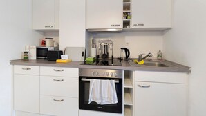 A modern kitchen with white cabinets, a built-in oven, a microwave, and a coffee maker. - New Central Apartment with Wi-Fi in Stuttgart (Stuttgart)