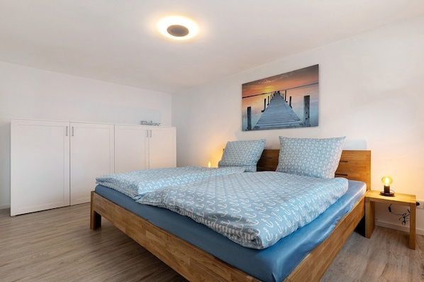 A bedroom with a bed, a nightstand, a wall-mounted painting, and a wardrobe.