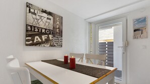 Ein Essbereich mit einem weißen Tisch, zwei roten Kerzen und einem Kunstwerk an der Wand.