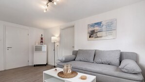 Ein modernes Wohnzimmer mit einem grauen Sofa, einem weißen Couchtisch und einer Lampe.