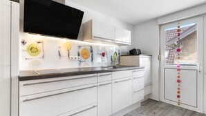 A modern kitchen with white cabinets, a black countertop, and a window with decorative elements.