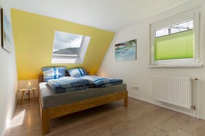 Une chambre à coucher avec un lit, une fenêtre, un radiateur et une petite table avec une lampe.