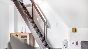 A modern interior with a wooden staircase, a small wooden table, a white lantern, and a gray sofa. - Apartment "Bayerl" with Mountain View, Balcony and Wi-Fi (Kirchseeon)