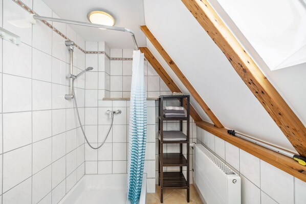 Una ducha con puerta de vidrio, un perchero y estructura de madera con vigas.