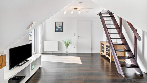 A modern interior with a TV on a white console, a wooden ladder, and a white door. - Apartment "Bayerl" with Mountain View, Balcony and Wi-Fi (Kirchseeon)