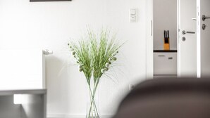 A clear view of a room with a white wall, a door, and a clear vase with green plants on the floor. - Apartment "Bayerl" with Mountain View, Balcony and Wi-Fi (Kirchseeon)