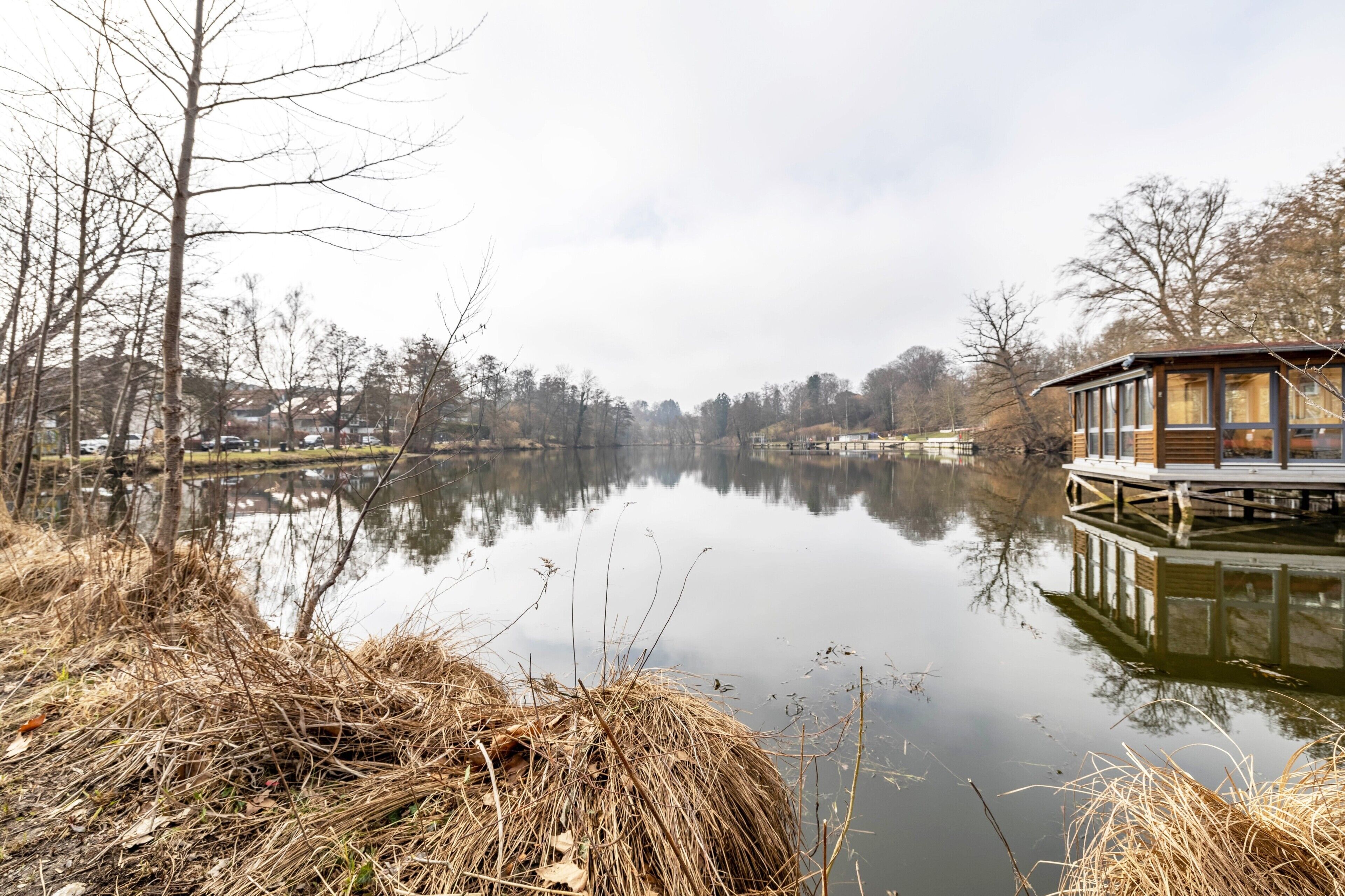 Ein ruhiger See mit einer hölzernen Mole und einer kleinen Holzhütte.