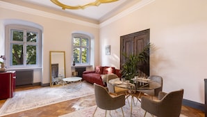 A room with a dining table, chairs, a red sofa, a mirror, and a large window. - Apartment 'Suite' with Shared Pool, Shared Terrace and Wi-Fi (Vitzenburg)