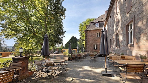 An outdoor patio with stone flooring, wooden tables and chairs, and umbrellas. - Apartment 'Suite' with Shared Pool, Shared Terrace and Wi-Fi (Vitzenburg)