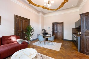 Un salon avec un canapé rouge, une table basse blanche et un coin repas avec deux chaises.