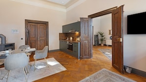 A spacious living area with a dining table, chairs, a kitchen with modern appliances, and a large TV mounted on the wall. - Apartment 'Suite' with Shared Pool, Shared Terrace and Wi-Fi (Vitzenburg)