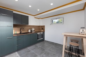 Una cocina moderna con armarios grises, encimera de madera y horno empotrado.