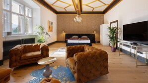 A modern hotel room with a large bed, two sofas, a TV, and a chandelier. - Apartment 'Eremitage' with Shared Pool, Shared Terrace and Wi-Fi (Vitzenburg)