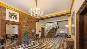 A checkered floor, a chandelier, a staircase, and a dining area with chairs and a table. - Apartment 'Eremitage' with Shared Pool, Shared Terrace and Wi-Fi (Vitzenburg)