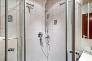 A modern bathroom with a glass-enclosed shower, a toilet, and a sink.