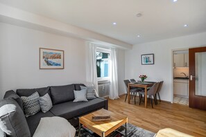Un salon moderne avec un canapé gris, une table basse en bois et un coin repas comprenant une table et des chaises.