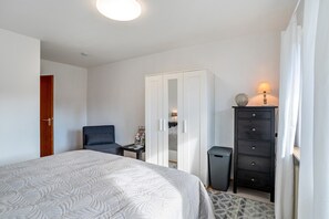 Una camera da letto con un letto, un armadio, una scrivania e una lampada.