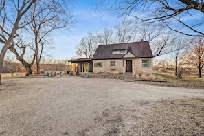 A house with a stone exterior, a front porch, and a gravel driveway.