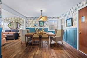 A dining area with a wooden table, wicker chairs, and a hanging light fixture.