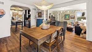 Un comedor con mesa de madera, sillas de mimbre y una lámpara colgante.