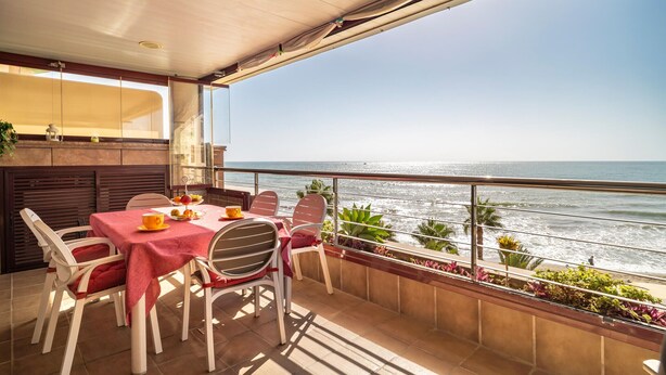 Un balcon avec une table dressée pour deux personnes, donnant sur la mer.