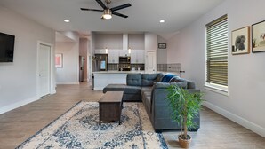 Una sala de estar moderna con un sofá modular, una mesa de centro y un ventanal con persianas.