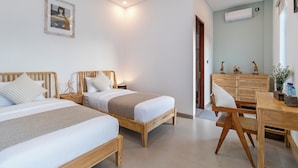 A hotel room with two wooden beds, a wooden desk, and a wicker chair. - Villa Blessing Bali (Ungasan)