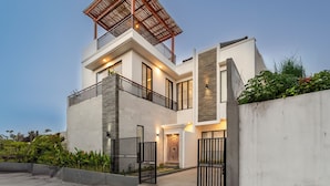 A modern two-story house with a balcony, a wooden pergola, and a gated entrance. - Villa Blessing Bali (Ungasan)