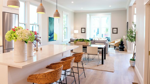 A modern kitchen with a large island, bar stools, and hanging pendant lights.