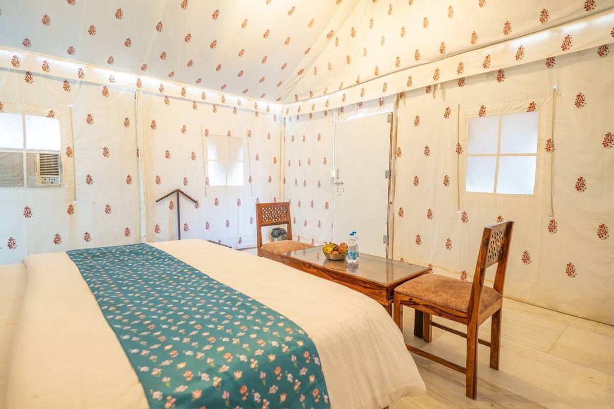 A room with a bed, a wooden table with a chair, and a window.