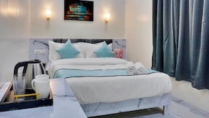 Una habitación de hotel con una cama, una mesita de noche, un hervidor y una bandeja con vasos y tazas.