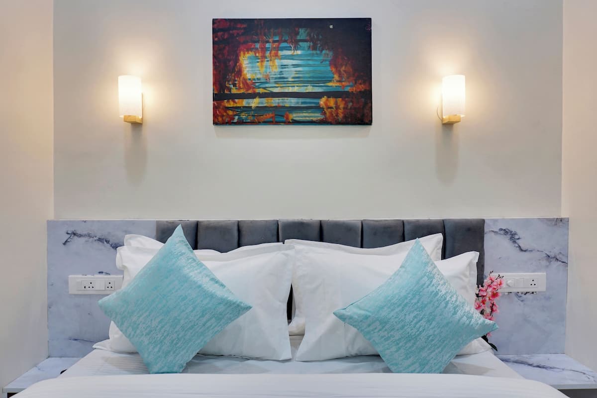 Un letto con una testata in marmo, due cuscini azzurri e un quadro appeso sopra.