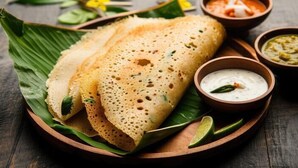 Un plato con dos dosas, un cuenco de chutney de coco y un cuenco de sambar.