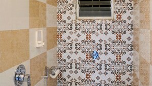 Un baño pequeño con inodoro, ducha y ventana con ventilación.